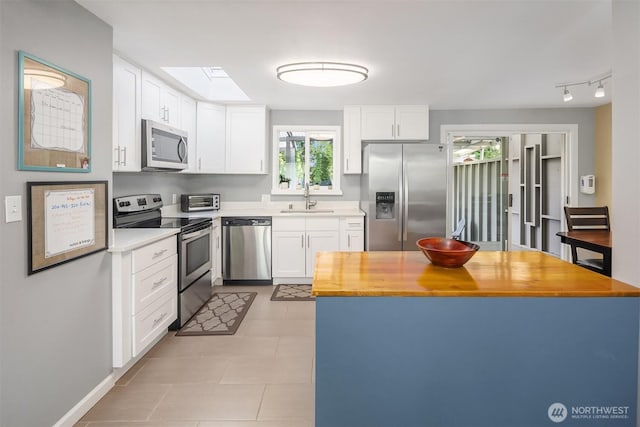 18312 73rd Ave W, Edmonds, WA 98026 - kitchen with stainless steel appliances, a sink, butcher block countertops, white cabinetry, and a skylight
