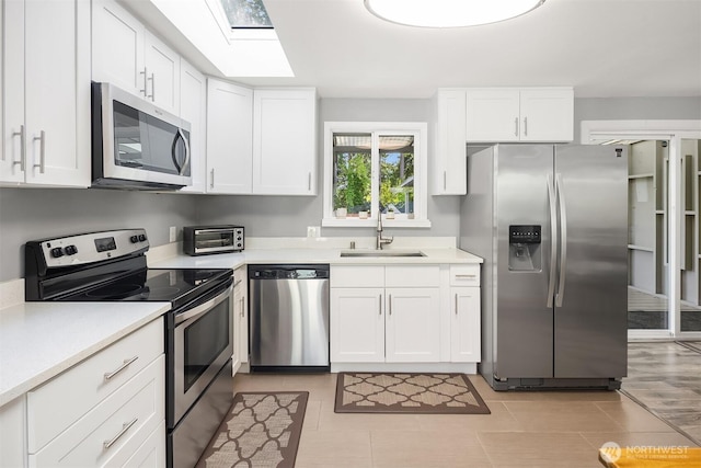 18312 73rd Ave W, Edmonds, WA 98026 - kitchen with stainless steel appliances, a sink, white cabinetry, light countertops, and a skylight