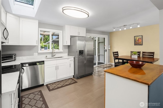 18312 73rd Ave W, Edmonds, WA 98026 - kitchen featuring appliances with stainless steel finishes, a sink, a skylight, white cabinetry, and butcher block countertops