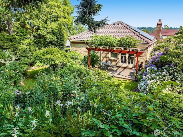 6045 Seward Park Ave S, Seattle, WA 98118 - rear view of property featuring a tiled roof, brick siding, roof mounted solar panels, and a patio area