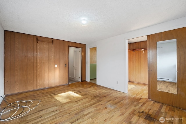 8608 16th Ave SW, Seattle, WA 98106 - unfurnished bedroom with a baseboard heating unit, light wood-style floors, wood walls, and a textured ceiling