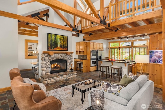 16375 NE 44th Ct, Redmond, WA 98052 - living area featuring stone tile floors, baseboards, a stone fireplace, beam ceiling, and high vaulted ceiling