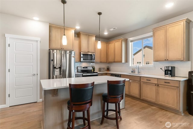 707 I St NE, Quincy, WA 98848 - kitchen featuring stainless steel appliances, a sink, decorative backsplash, light wood finished floors, and a center island