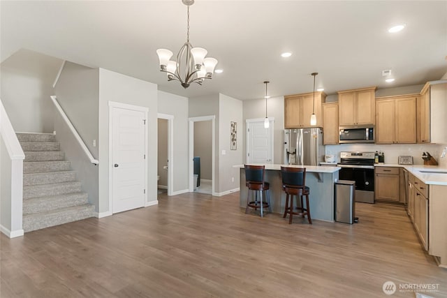 707 I St NE, Quincy, WA 98848 - kitchen with appliances with stainless steel finishes, a sink, a center island, a kitchen bar, and light wood-type flooring