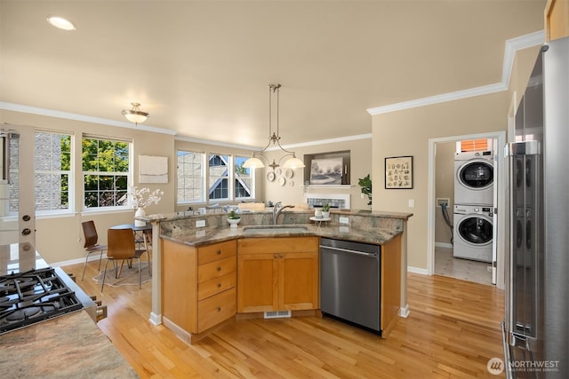19799 NE Ash Crest Loop, Poulsbo, WA 98370 - kitchen featuring stainless steel appliances, stacked washer and clothes dryer, a sink, ornamental molding, and light wood finished floors