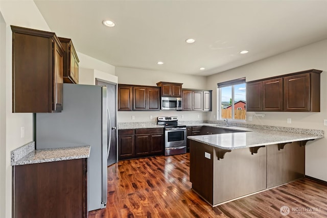2212 N Creeksedge Way, Ellensburg, WA 98926 - kitchen featuring stainless steel appliances, a peninsula, dark brown cabinets, a kitchen breakfast bar, and dark wood-style flooring
