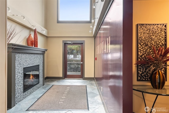 22910 90th Ave W Unit E406, Edmonds, WA 98026 - foyer entrance with rail lighting, a tiled fireplace, a high ceiling, and baseboards