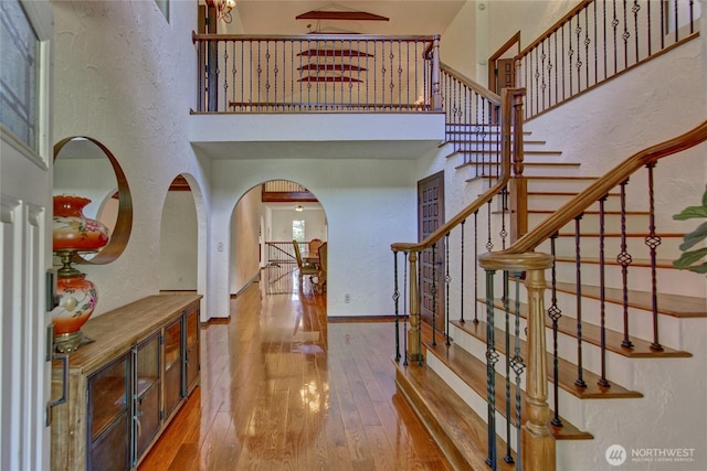 13311 SE 290th St, Auburn, WA 98092 - foyer with arched walkways, a textured wall, hardwood / wood-style flooring, a towering ceiling, and stairs