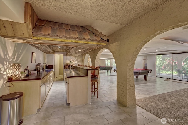 13311 SE 290th St, Auburn, WA 98092 - kitchen featuring arched walkways, billiards table, dark countertops, a sink, and light tile patterned floors