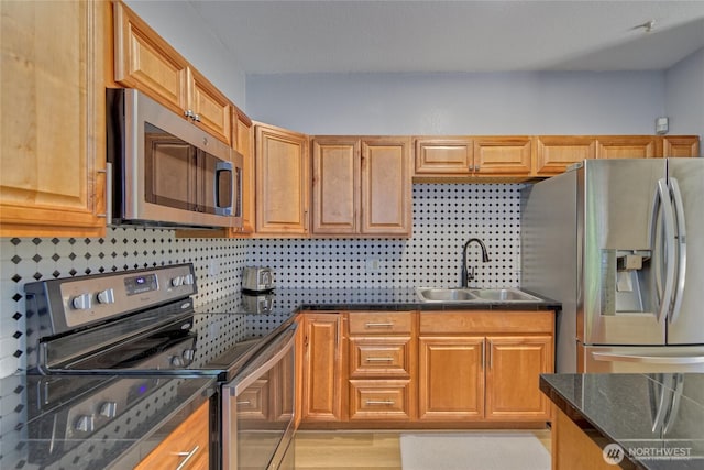 13311 SE 290th St, Auburn, WA 98092 - kitchen featuring stainless steel appliances, a sink, dark countertops, decorative backsplash, and light wood-style flooring