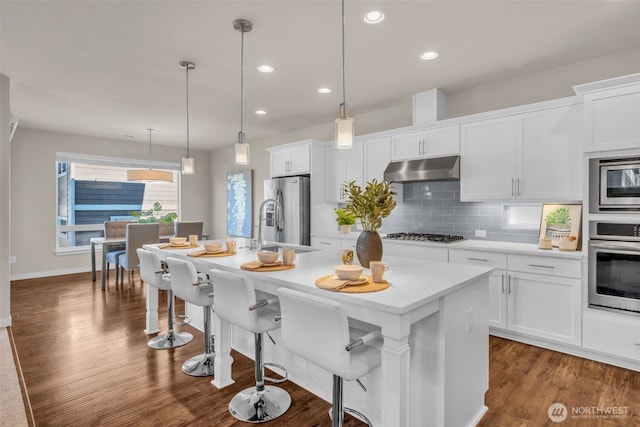 3071 S 276th Ct, Auburn, WA 98001 - kitchen featuring appliances with stainless steel finishes, under cabinet range hood, an island with sink, white cabinets, and recessed lighting