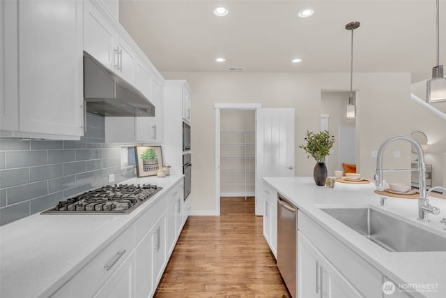 3071 S 276th Ct, Auburn, WA 98001 - kitchen featuring appliances with stainless steel finishes, under cabinet range hood, white cabinets, light wood-type flooring, and light countertops