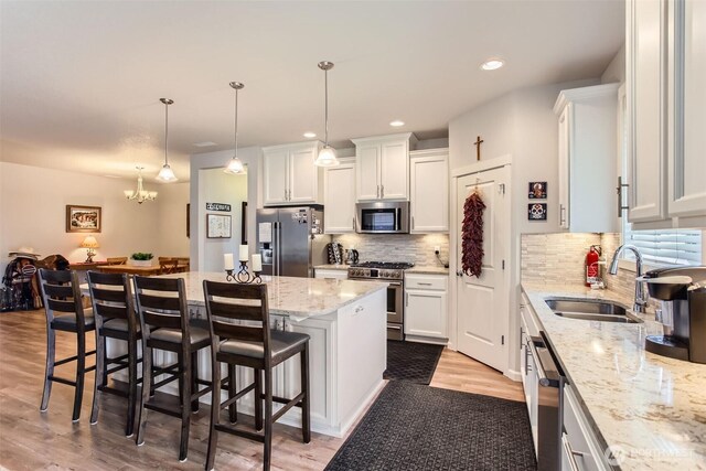 12911 NE 61st Ave, Vancouver, WA 98686 - kitchen with stainless steel appliances, a sink, white cabinetry, light wood-type flooring, and a center island