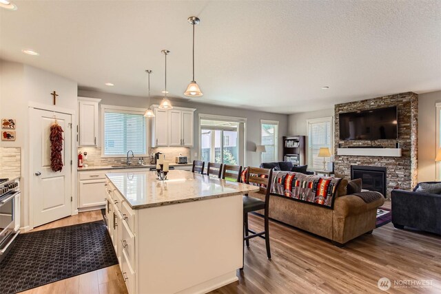 12911 NE 61st Ave, Vancouver, WA 98686 - kitchen featuring open floor plan, a kitchen breakfast bar, wood finished floors, a sink, and white cabinetry