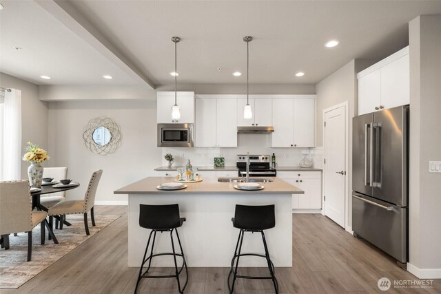 3123 148th St SW Unit A6, Lynnwood, WA 98087 - kitchen with appliances with stainless steel finishes, a sink, a kitchen island with sink, a breakfast bar, and light wood finished floors