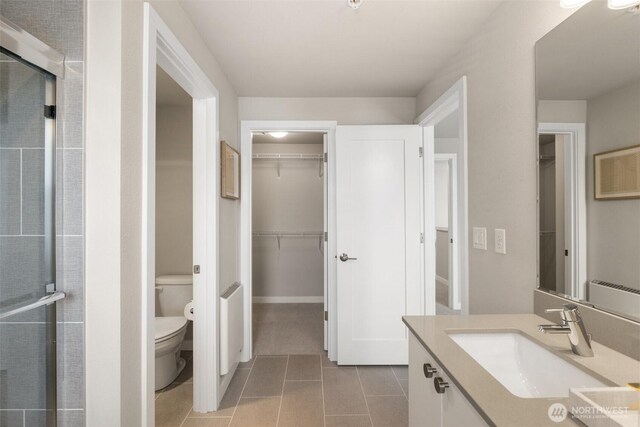 3123 148th St SW Unit A6, Lynnwood, WA 98087 - bathroom featuring toilet, vanity, a stall shower, tile patterned flooring, and a walk in closet