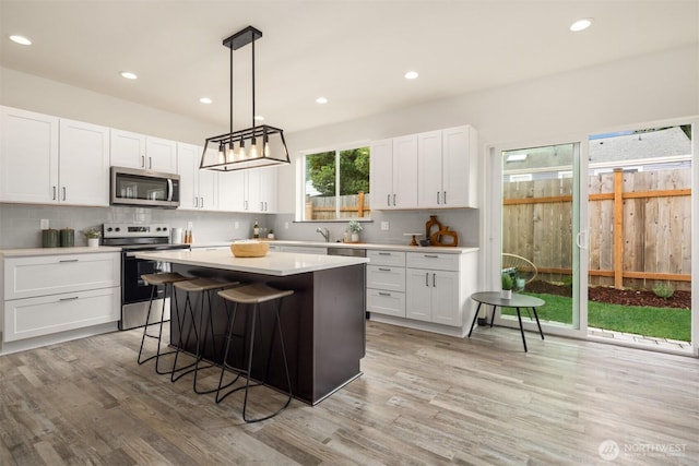 9245 Kelsey Ln SW, Seattle, WA 98106 - kitchen featuring stainless steel appliances, light wood-style floors, light countertops, white cabinets, and recessed lighting