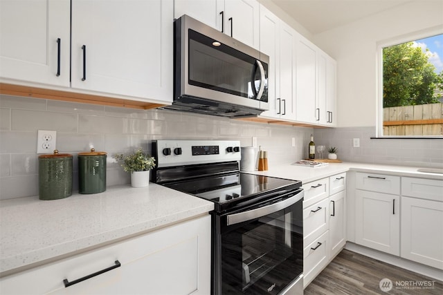 9245 Kelsey Ln SW, Seattle, WA 98106 - kitchen featuring appliances with stainless steel finishes, white cabinetry, tasteful backsplash, light stone counters, and dark wood finished floors