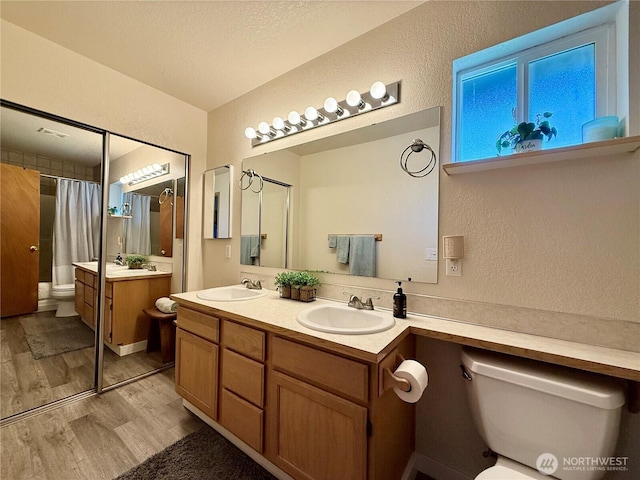 4304 Seville Dr SE, Lacey, WA 98503 - full bath with toilet, wood finished floors, a textured wall, double vanity, and a shower with shower curtain