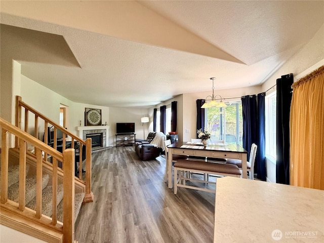 4304 Seville Dr SE, Lacey, WA 98503 - dining area featuring a textured ceiling, wood finished floors, a tile fireplace, stairway, and vaulted ceiling