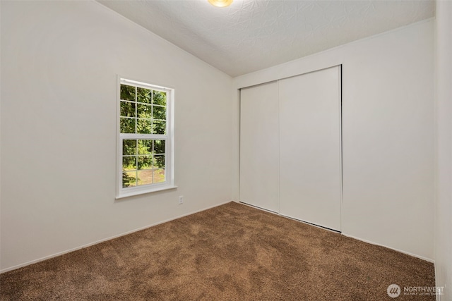 16605 259th Avenue Ct E, Buckley, WA 98321 - unfurnished bedroom with dark colored carpet, a closet, vaulted ceiling, and a textured ceiling