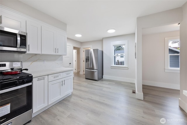 2333 31st Ave S, Seattle, WA 98144 - kitchen with stainless steel appliances, white cabinetry, baseboards, light wood finished floors, and backsplash