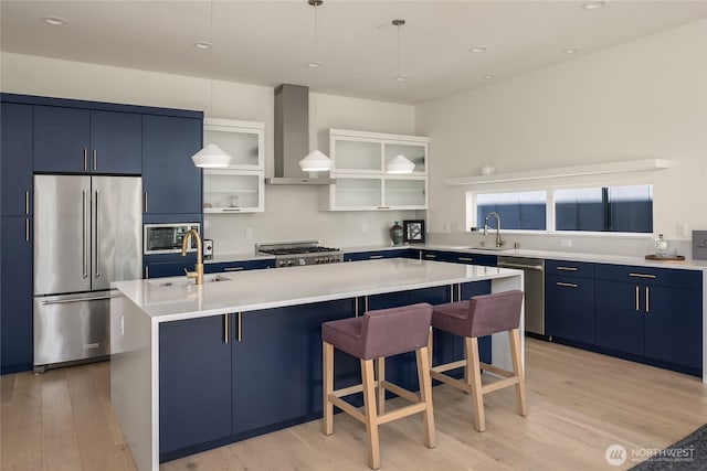 10227 26th Ave SW, Seattle, WA 98146 - kitchen featuring appliances with stainless steel finishes, blue cabinetry, wall chimney range hood, a sink, and recessed lighting