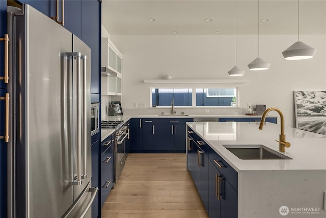 10227 26th Ave SW, Seattle, WA 98146 - kitchen featuring high quality appliances, blue cabinetry, a sink, light wood finished floors, and recessed lighting