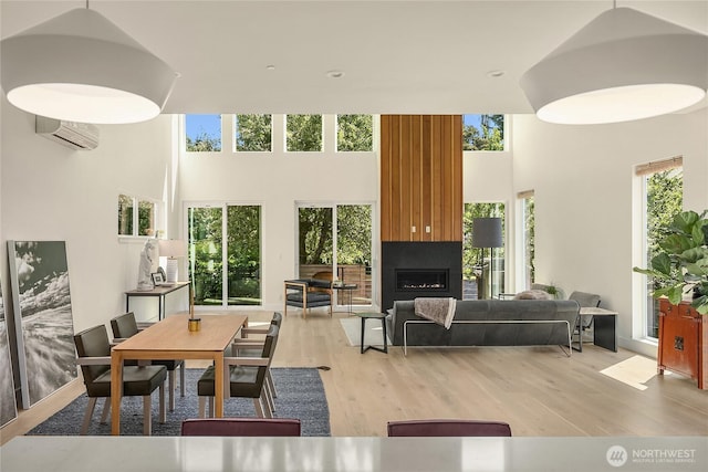 10227 26th Ave SW, Seattle, WA 98146 - dining room with a towering ceiling, healthy amount of natural light, a wall mounted air conditioner, a fireplace, and light wood finished floors
