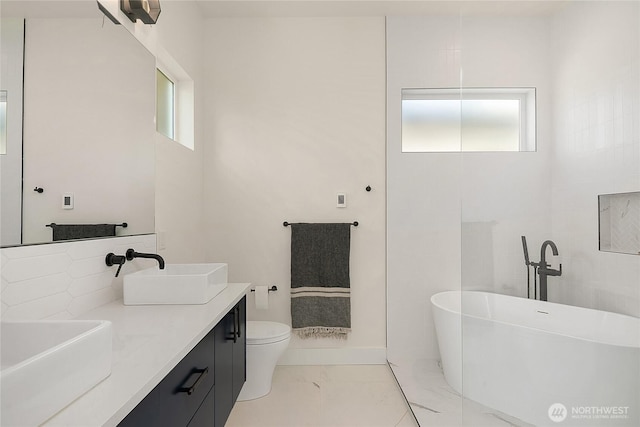 10227 26th Ave SW, Seattle, WA 98146 - full bathroom featuring marble look tiles, a freestanding bath, double vanity, and toilet