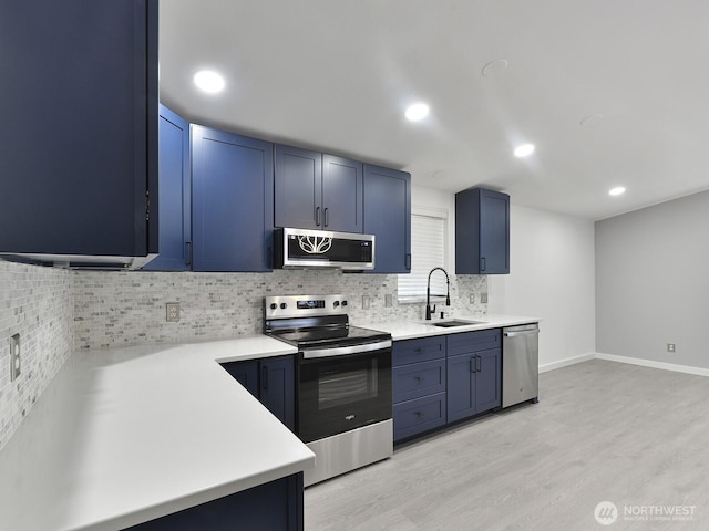 27460 149th Pl SE Unit 85, Kent, WA 98042 - kitchen featuring appliances with stainless steel finishes, a sink, blue cabinetry, decorative backsplash, and light wood-style floors