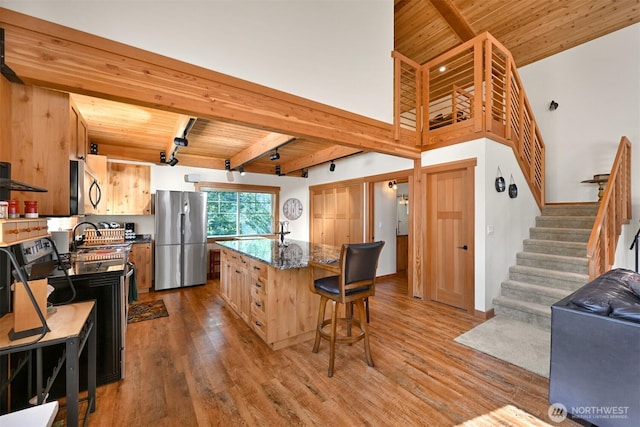 9135 Custer School Rd, Custer, WA 98240 - kitchen featuring stainless steel appliances, wood ceiling with exposed beams, wood finished floors, a kitchen breakfast bar, and a center island