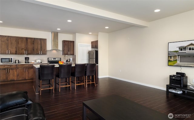 421 Lofgrin Rd, Sequim, WA 98382 - kitchen with wall chimney range hood, appliances with stainless steel finishes, dark wood-style floors, a kitchen breakfast bar, and open floor plan