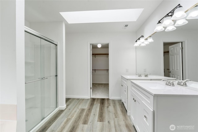 1258 NW Timber Shadow Ct, Silverdale, WA 98380 - full bathroom with a skylight, a stall shower, wood finished floors, and double vanity