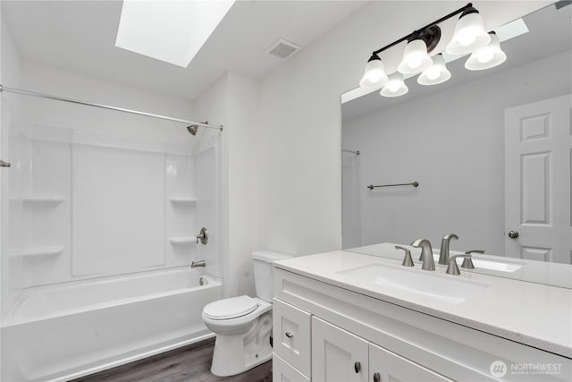 1258 NW Timber Shadow Ct, Silverdale, WA 98380 - bathroom featuring wood finished floors, toilet, vanity, a skylight, and bathing tub / shower combination