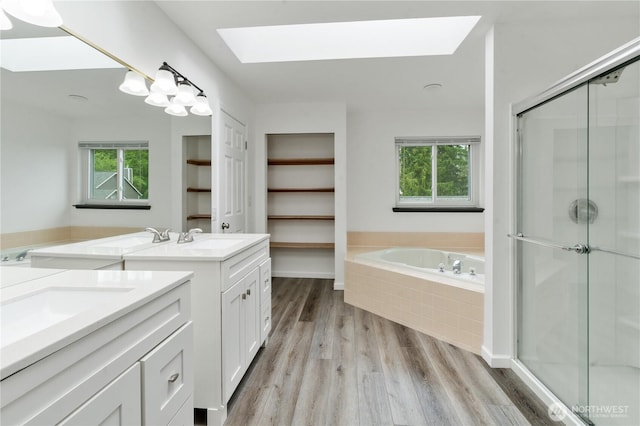 1258 NW Timber Shadow Ct, Silverdale, WA 98380 - bathroom featuring a skylight, two vanities, wood finished floors, and healthy amount of natural light