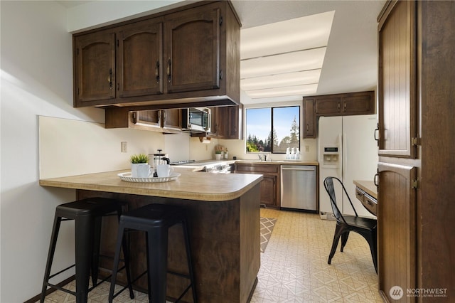 18801 86th Pl W, Edmonds, WA 98026 - kitchen with appliances with stainless steel finishes, a peninsula, dark brown cabinets, and a breakfast bar