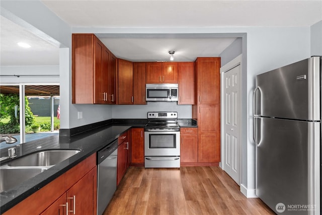 367 1st St SE, East Wenatchee, WA 98802 - kitchen featuring stainless steel appliances, light wood finished floors, a sink, dark stone countertops, and brown cabinetry