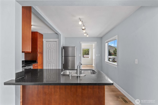 367 1st St SE, East Wenatchee, WA 98802 - kitchen featuring stainless steel appliances, a sink, baseboards, light wood finished floors, and dark stone counters