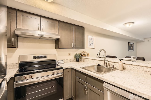 3022 SW Bradford St Unit 205, Seattle, WA 98126 - kitchen with appliances with stainless steel finishes, under cabinet range hood, a sink, a peninsula, and light stone counters