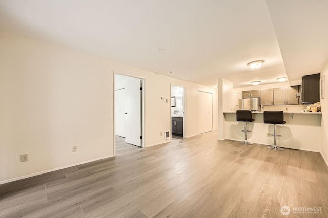 3022 SW Bradford St Unit 205, Seattle, WA 98126 - unfurnished living room featuring light wood finished floors and baseboards