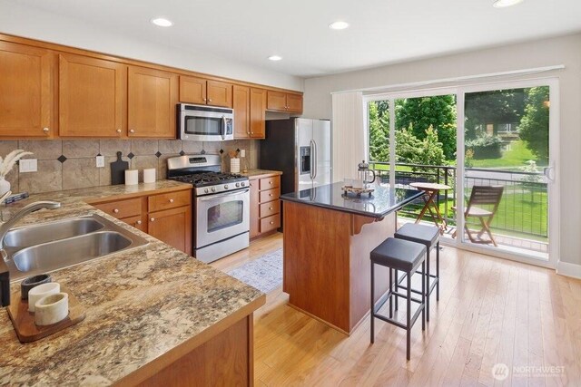 7121 Shinkle Pl SW, Seattle, WA 98106 - kitchen featuring stainless steel appliances, a sink, brown cabinets, a kitchen bar, and recessed lighting