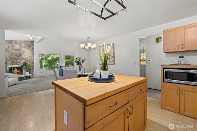 7223 NE 160th St, Kenmore, WA 98028 - kitchen featuring stainless steel microwave, wood counters, light wood finished floors, a chandelier, and a stone fireplace