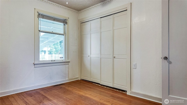 2502 Thurston Ave NE, Olympia, WA 98506 - unfurnished bedroom featuring light wood-style floors, baseboards, a closet, and wallpapered walls