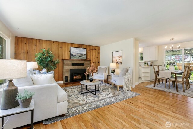 331 E 2nd St, North Bend, WA 98045 - living room with a chandelier, light wood-style floors, a fireplace, and wooden walls