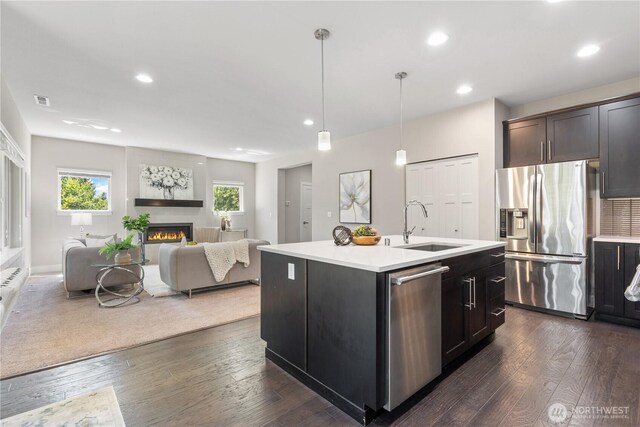 4008 223rd Pl SE, Bothell, WA 98021 - kitchen featuring appliances with stainless steel finishes, open floor plan, light countertops, a warm lit fireplace, and dark wood-type flooring