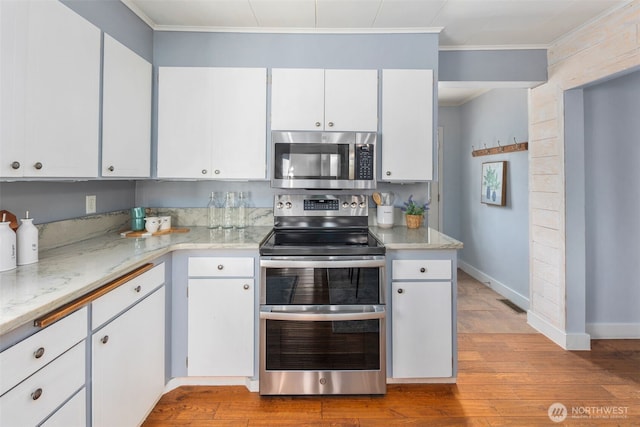 1254 Mchugh Ave, Enumclaw, WA 98022 - kitchen with stainless steel appliances, ornamental molding, wood finished floors, white cabinetry, and baseboards