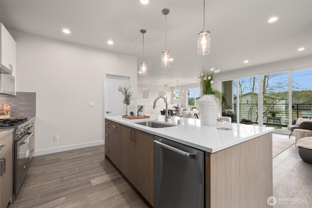 4576 22nd Ave SW, Seattle, WA 98106 - kitchen with appliances with stainless steel finishes, open floor plan, wood finished floors, light countertops, and a center island with sink