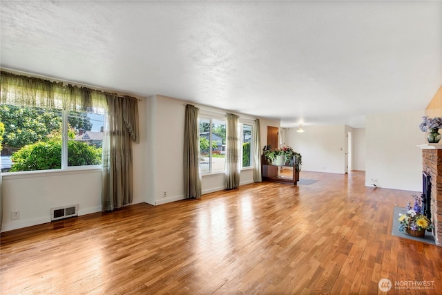 220 Alder Ave, Sumner, WA 98390 - unfurnished living room with light wood-type flooring, a brick fireplace, and baseboards
