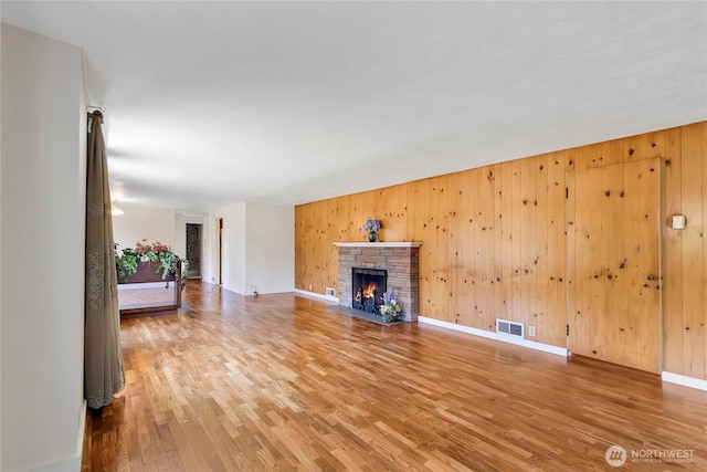 220 Alder Ave, Sumner, WA 98390 - unfurnished living room with wood finished floors, a warm lit fireplace, wood walls, and baseboards